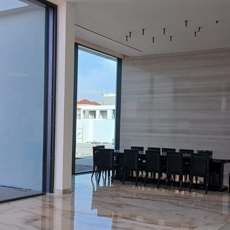 Marble flooring and floor-to-ceiling glazing in a villa dining area