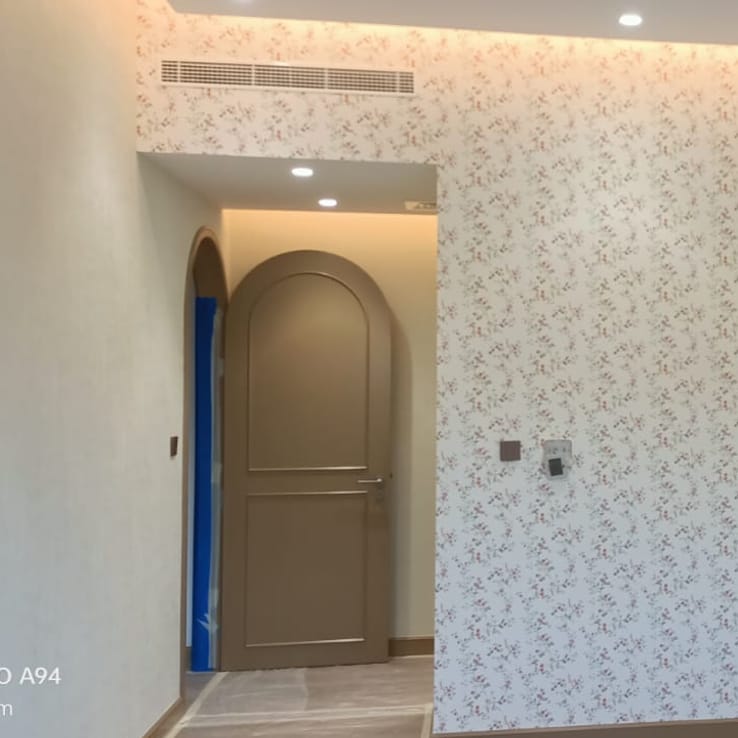 Floral wallpaper installed in a hallway with arched doorway