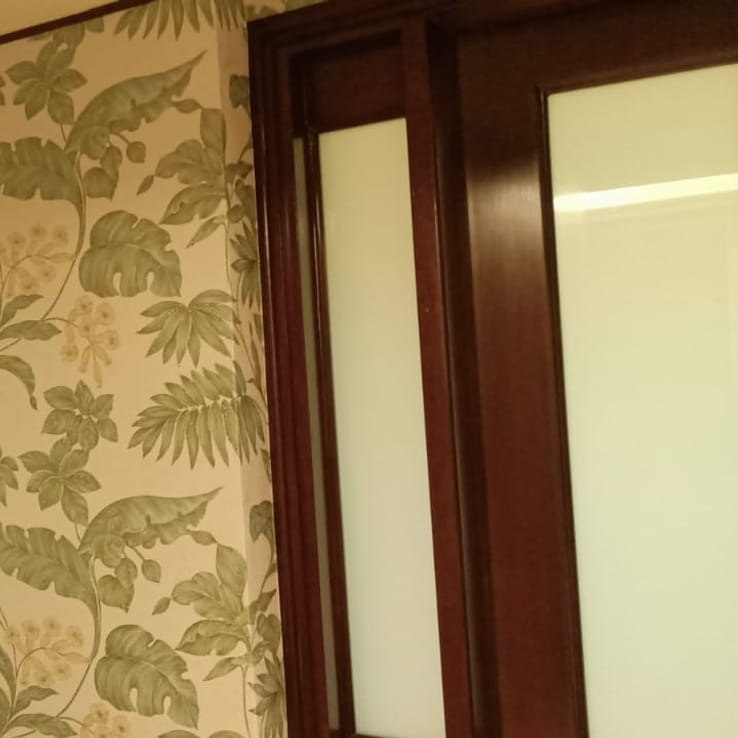 Tropical leaf-pattern wallpaper detail near a wooden door frame